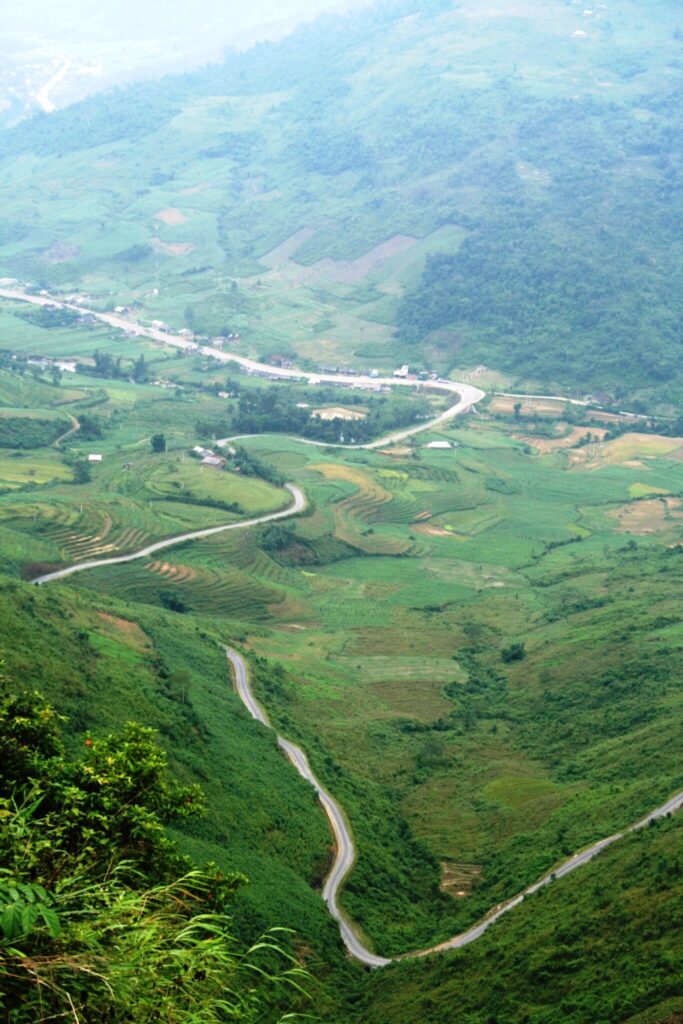 Winding road through green valleys seen from Bac Sum Pass on the way to Quan Ba Heaven Gate, Ha Giang.