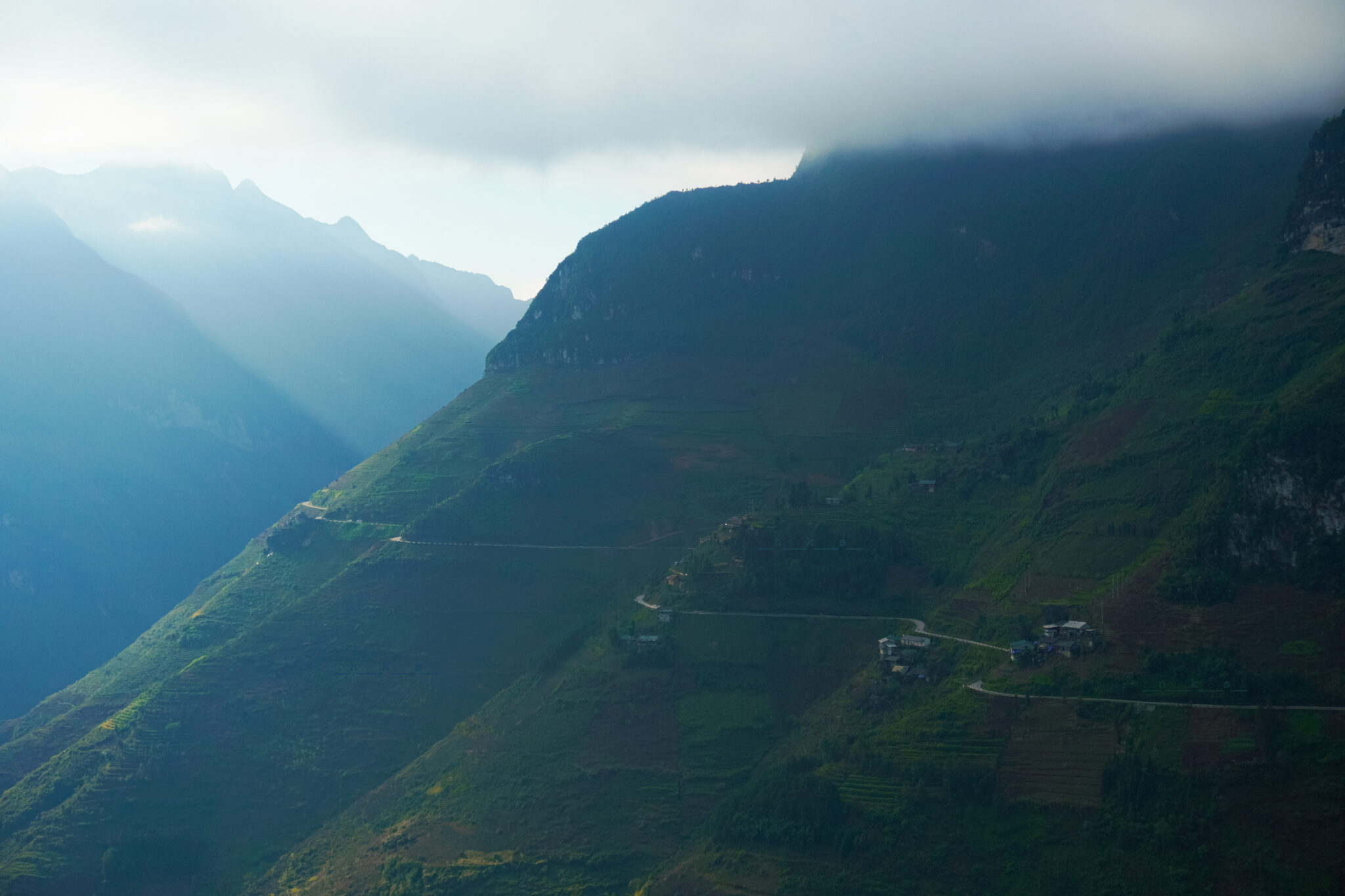 Ma Pi Leng Pass road winding through misty, cloud-covered mountains in Ha Giang, Vietnam
