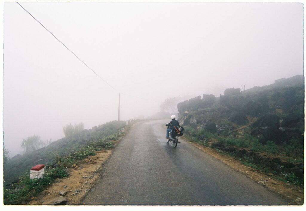 A solo rider with luggage on a foggy mountain road in Ha Giang, Vietnam