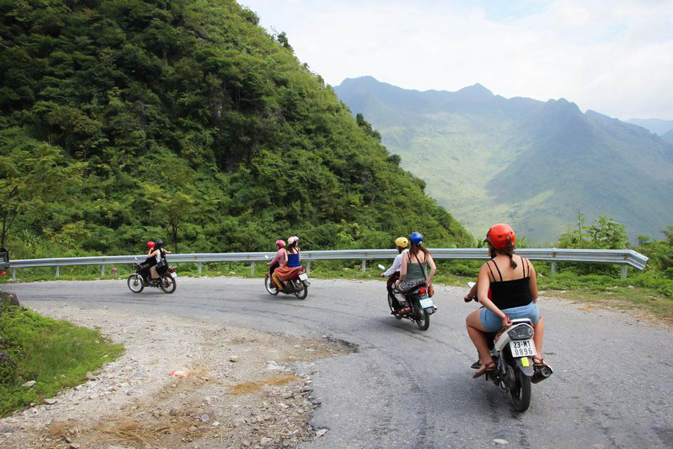 Travellers riding motorbikes two-up on a mountain road to Dong Van, Ha Giang, Vietnam