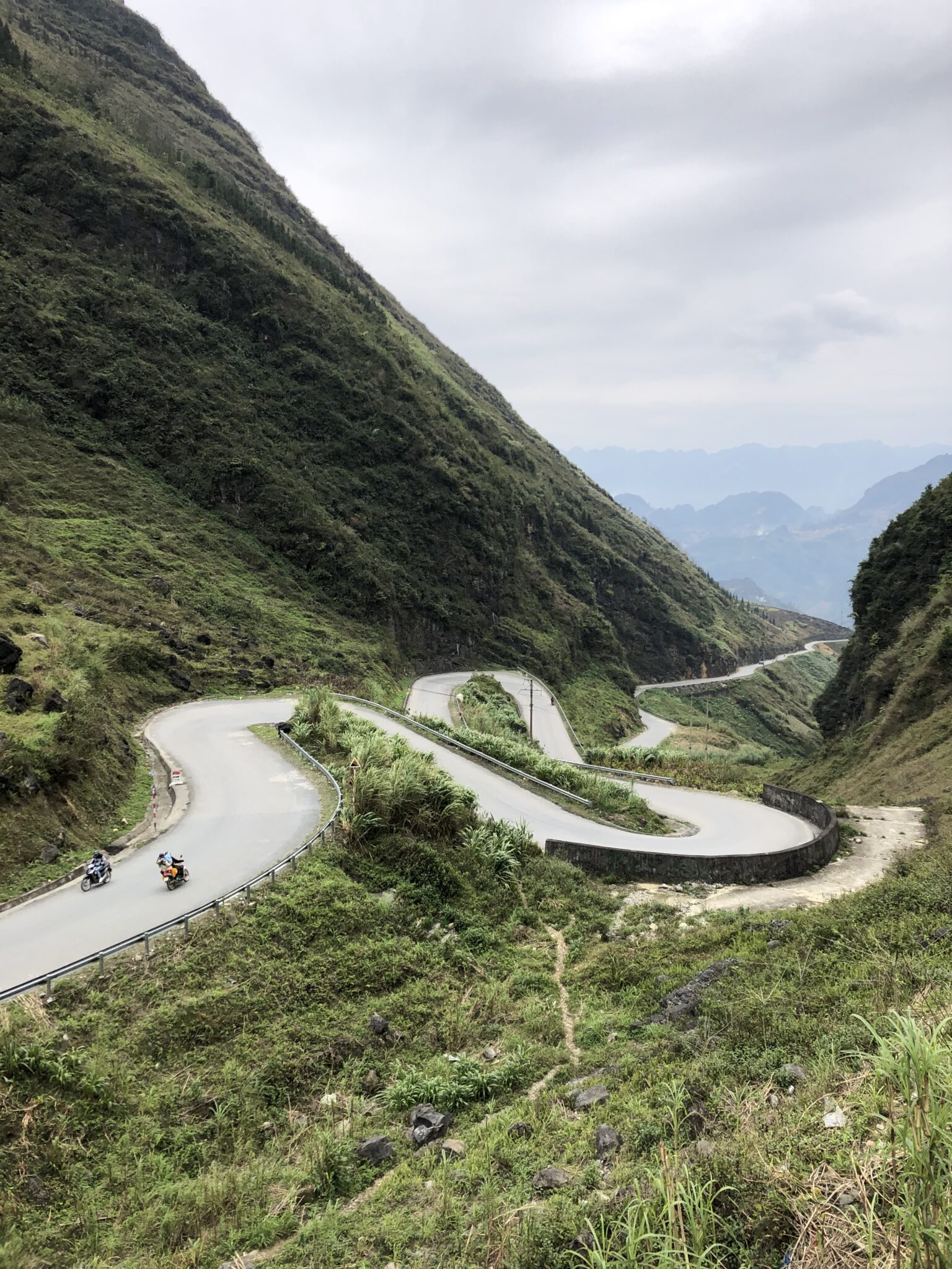 Two motorbikes riding the steep hairpin bends of the Ha Giang Loop in northern Vietnam